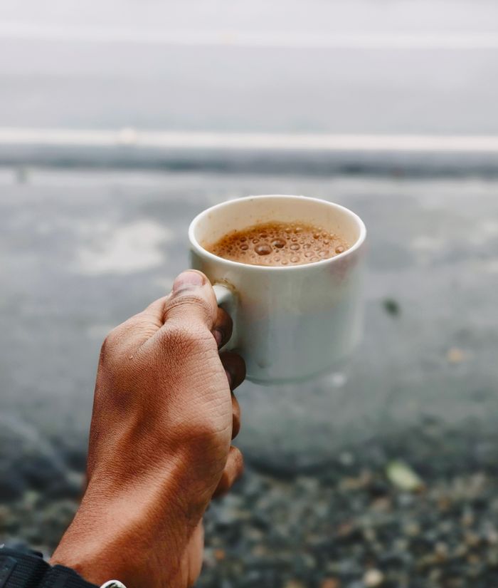 Crafting Captivating Headlines: Your awesome post title goes here A hand holding a steaming cup of tea outdoors, captured on a cloudy day in India.